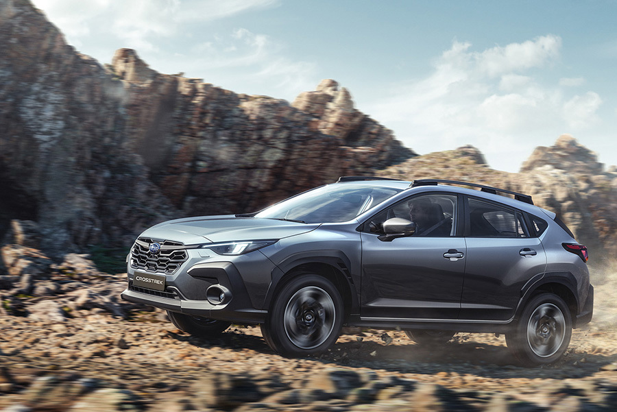 Subaru Crosstrek brauc pa grants ceļu, aiz automašīnas paceļas putekļu mākoņi.